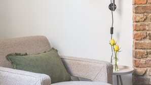 A cozy living room with a modern lamp, a green cushion, and a small table with a vase of yellow flowers. - Stylish & Petit Studio flat w/great tube connectio (Greater London)