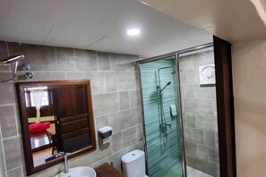 Un baño con cabina de ducha de vidrio, lavamanos e inodoro.