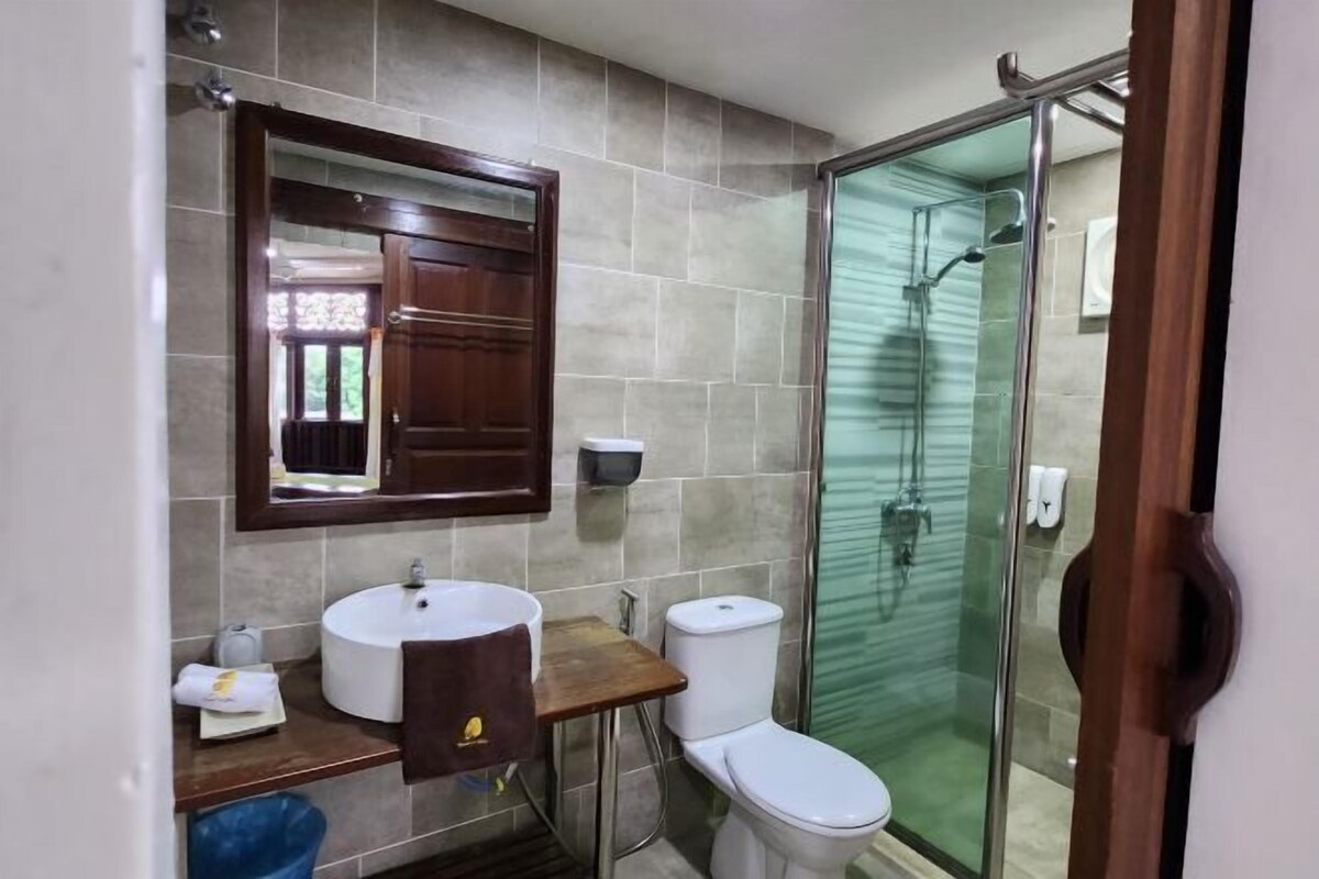 A bathroom with a sink, mirror, toilet, and glass shower enclosure.