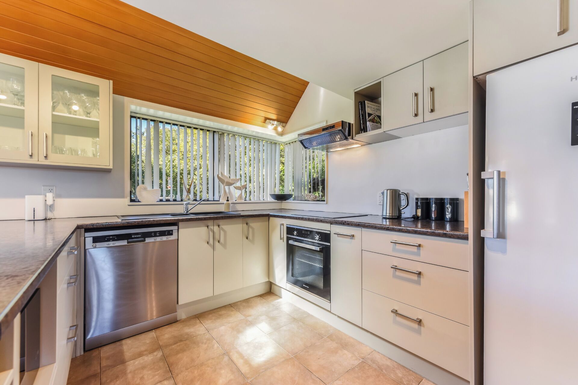 A modern kitchen with a dishwasher, oven, and a refrigerator.