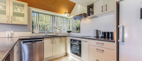 A modern kitchen with a dishwasher, oven, and a refrigerator.
