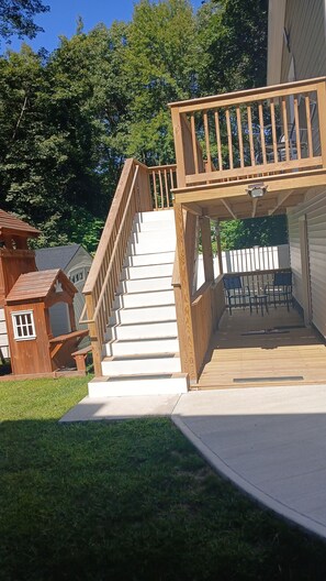 Une terrasse en bois avec un escalier menant à un espace abrité équipé de chaises.