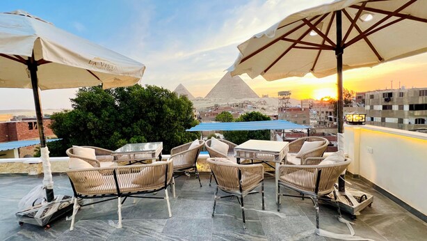 A rooftop terrace with wicker furniture, umbrellas, and a view of pyramids at sunset. - Vysta pyramids hotel Cairo 
View pyramids 
renovated rooms
Restaurant with view (Giza Governorate)