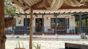Uma área de pátio externa com espaço de estar coberto, churrasqueira e plantas em vasos.