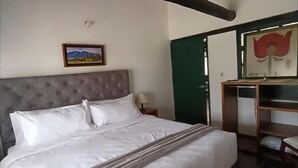 Quarto com uma cama grande, cabeceira, mesa de cabeceira, cômoda, espelho e um quadro na parede.