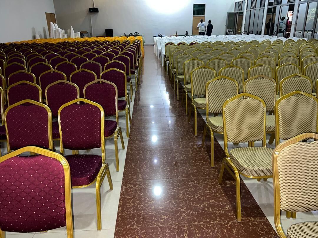 Une salle avec des rangées de chaises, dont certaines ont des montures dorées et d’autres un design différent.
