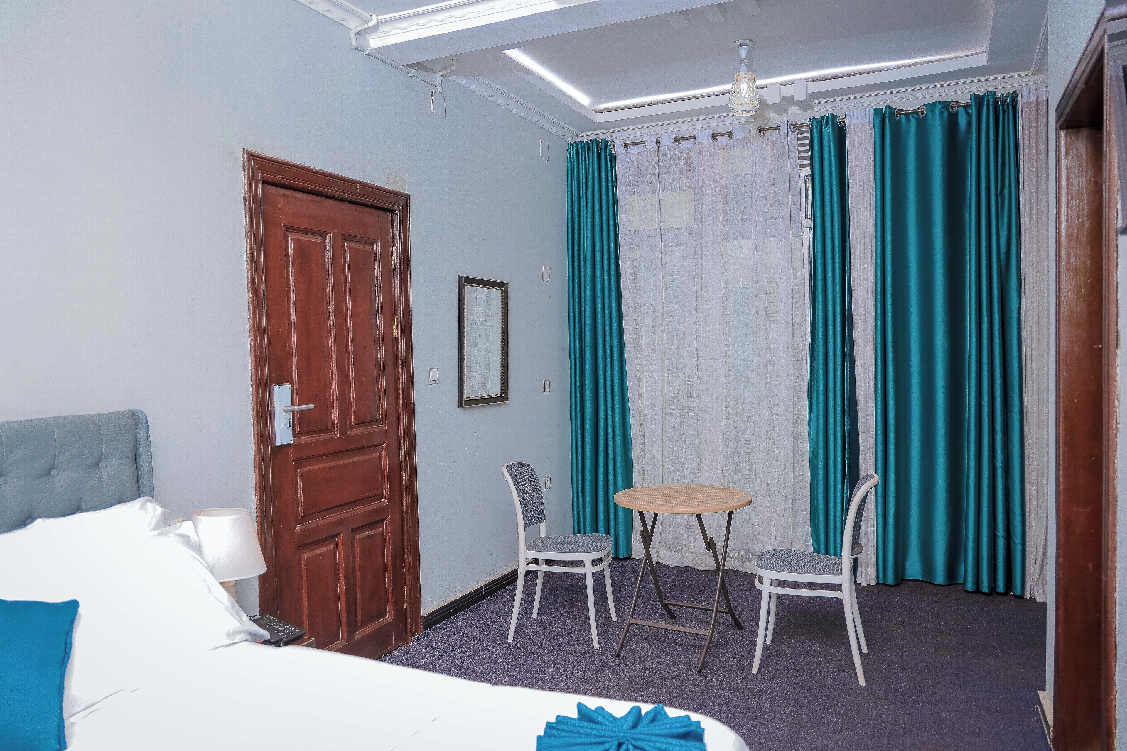 A hotel room with a bed, two chairs, a small table, and a door.