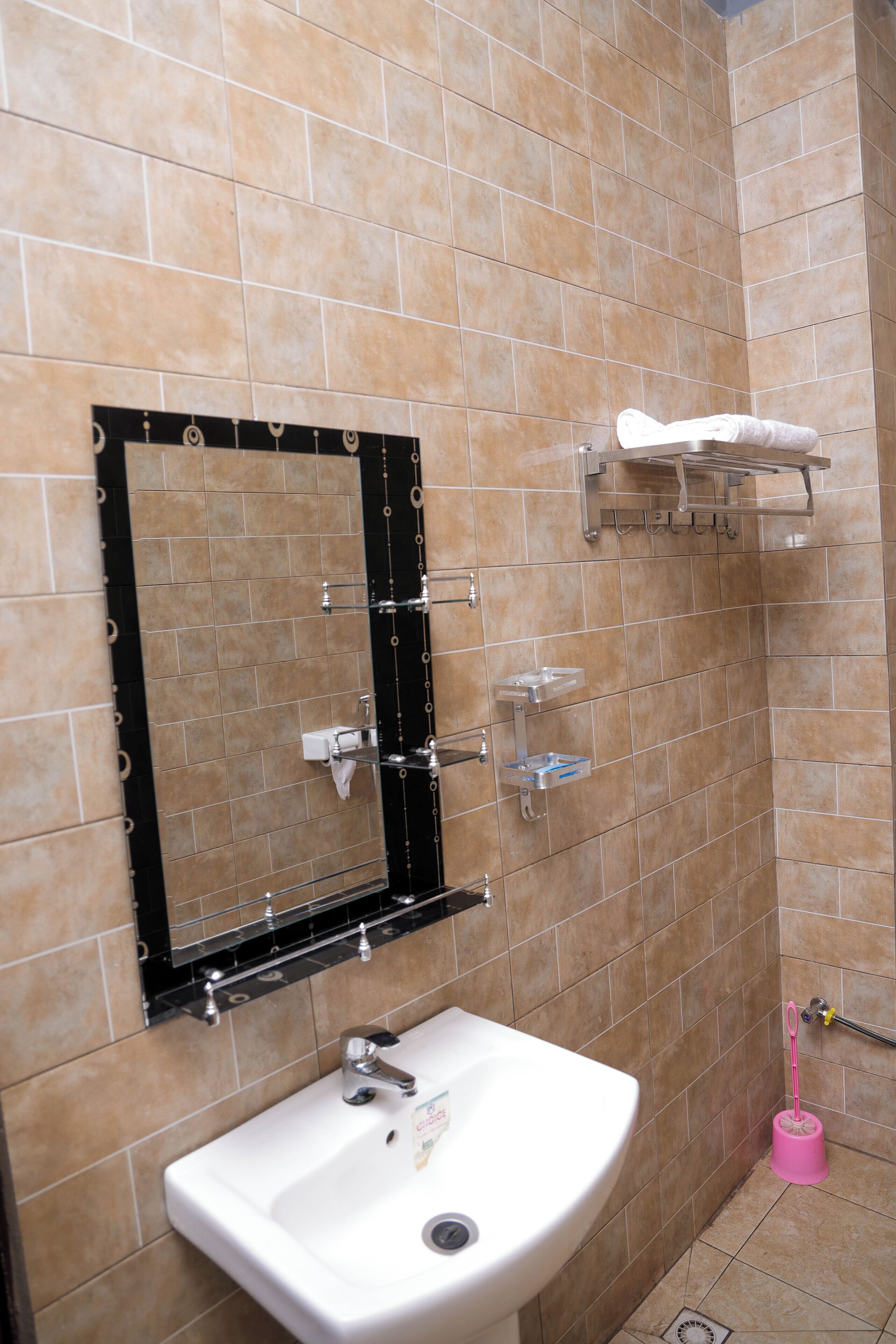A bathroom with beige tiles, a white sink, a mirror, and a towel rack.