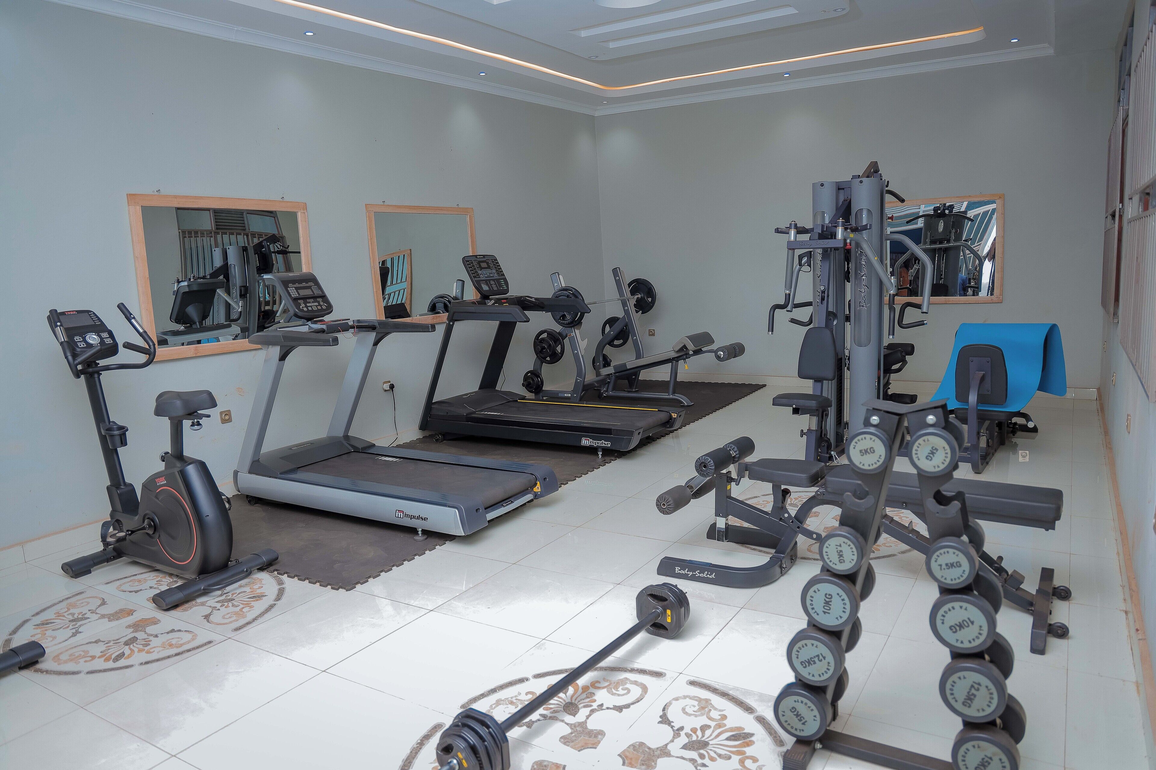 A home gym with a treadmill, elliptical, and weight bench.
