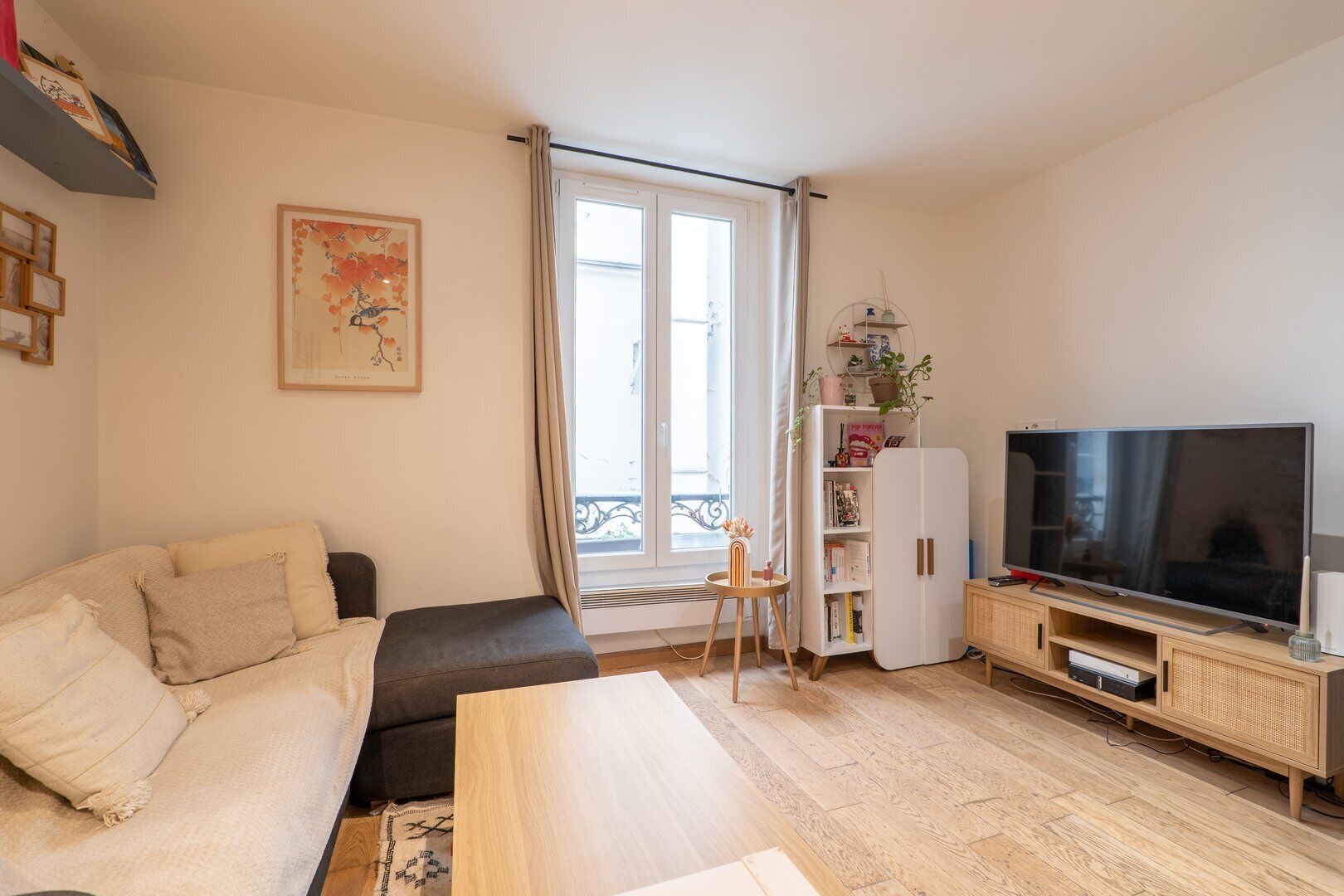 A living room with a sofa, a coffee table, a TV, and a bookshelf.