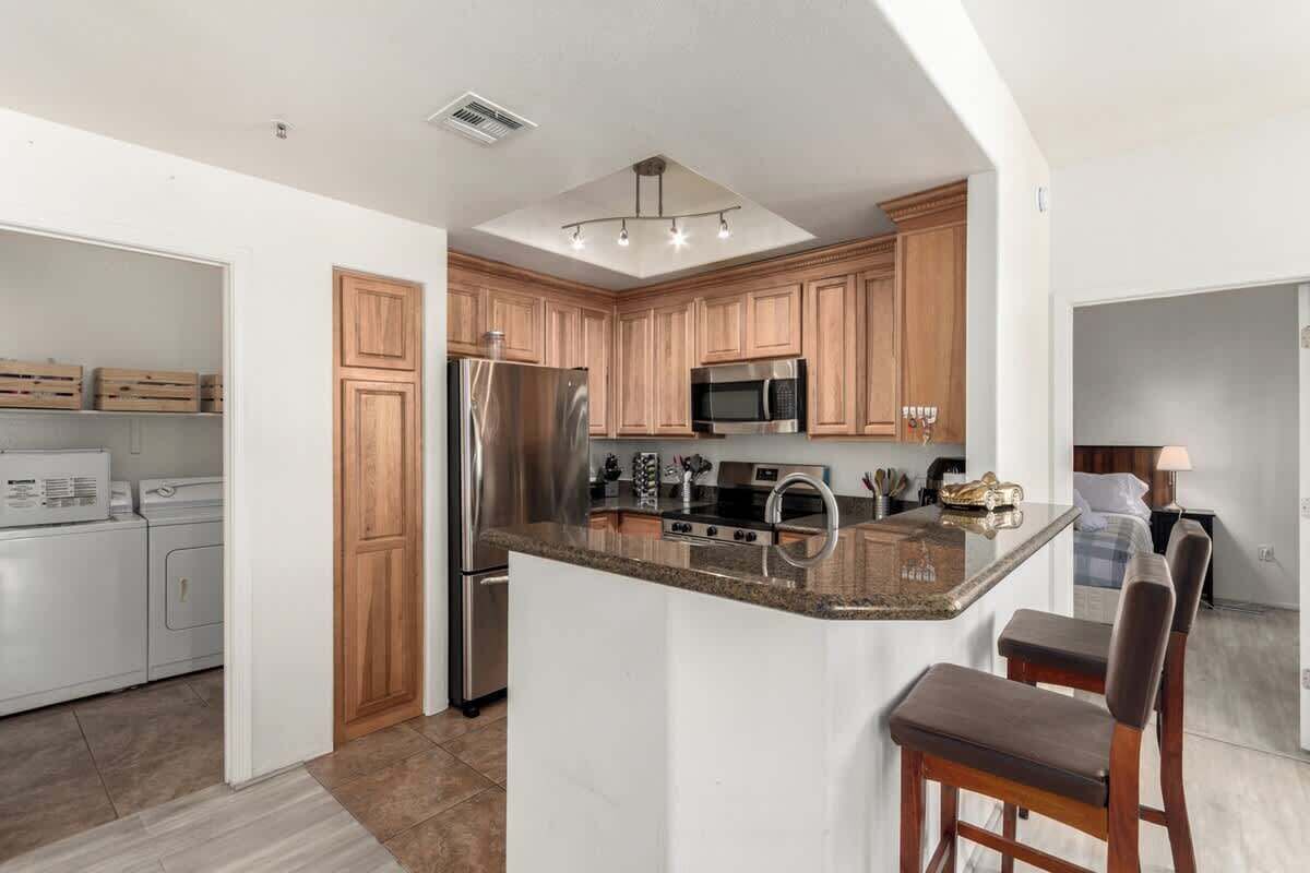 A modern kitchen with wooden cabinets, stainless steel appliances, and a central island with bar stools.