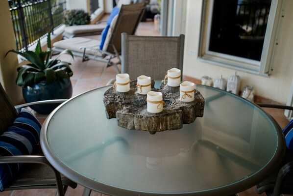 A round glass table with a rustic wooden centerpiece holding six candles.