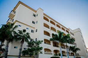 A multi-story hotel with balconies, palm trees, and a clear sky. - Las Mañanitas LM E3402 (San José del Cabo)