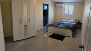 Un dormitorio con cama, armario, ventana y aire acondicionado.