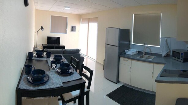 Una cocina compacta con comedor, refrigerador, microondas y pileta.