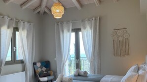 A bedroom with a high ceiling, two beds, a chair, a radiator, and a window with curtains.