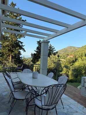 Un espace extérieur abrité, avec une table et des chaises, offrant une vue sur un paysage montagneux.