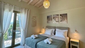 A bedroom with a large bed, two bedside tables, a ceiling fan, and a view of the outdoors.