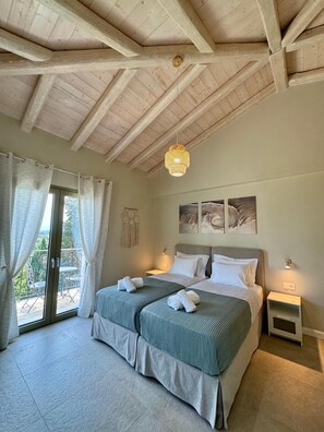 A bedroom with a large bed, two bedside tables, a ceiling fan, and a view of the outdoors.
