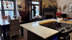 Une cuisine moderne dotée d’un îlot central, d’une cheminée et d’un coin repas avec des meubles en osier.