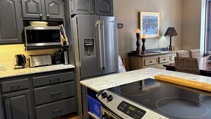 Une cuisine moderne avec des meubles de couleur sombre, des appareils électroménagers en acier inoxydable, un four à micro-ondes, un grille-pain et une cuisinière intégrée.