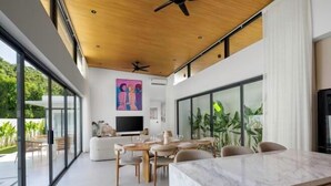 A modern interior with a dining area, a TV, and large windows.