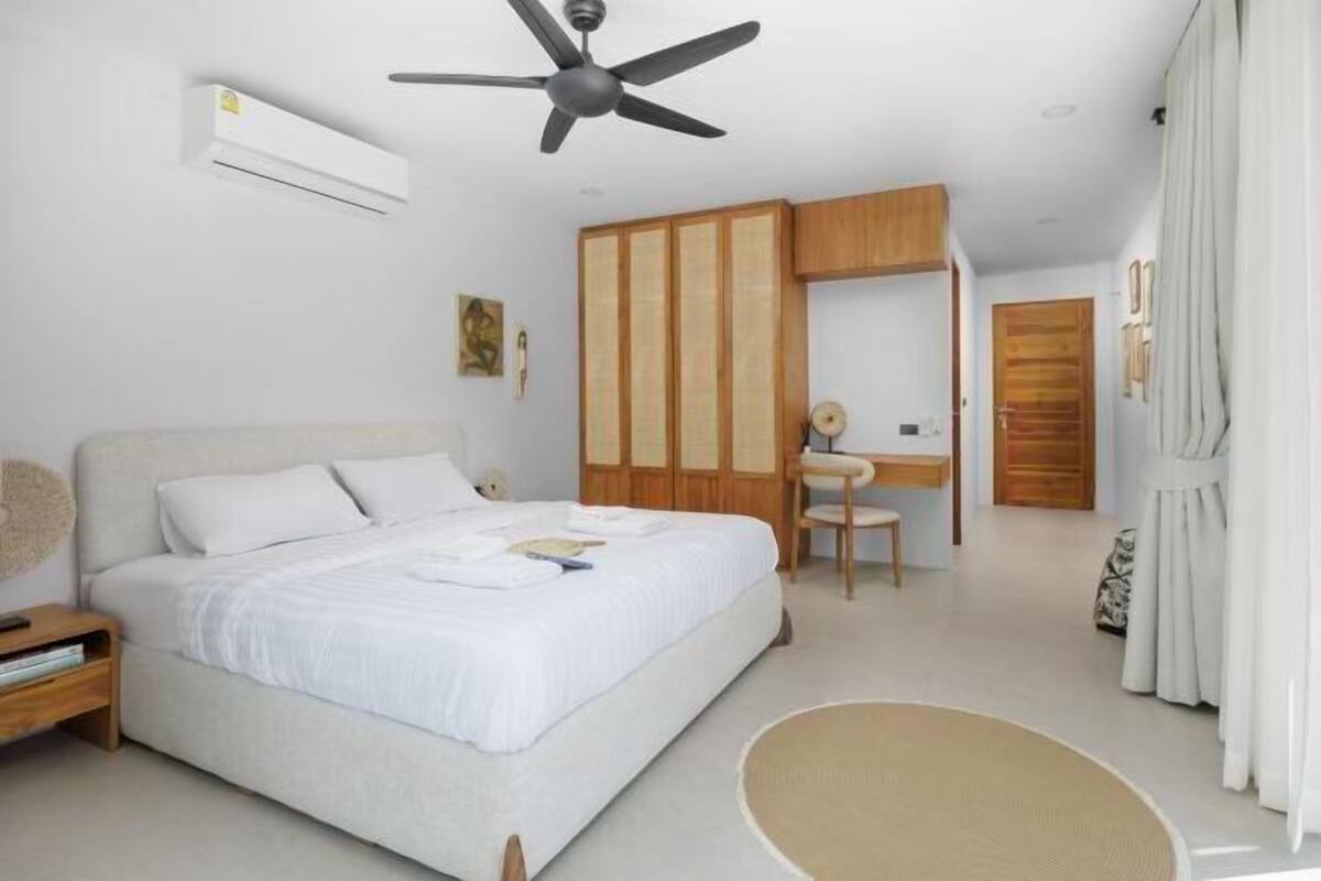 Une chambre à coucher comprenant un lit, une table de chevet, un bureau, une chaise et une armoire.
