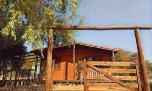 A wooden cabin with a metal gate, surrounded by a fence and trees. - Miramar cabin a few meters from the beach (Playa Grande)