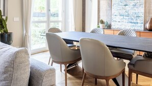 Een moderne eethoek met een lange tafel, verschillende stoelen en hanglampen.
