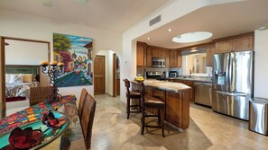 A modern kitchen with wooden cabinets, stainless steel appliances, and a central island with bar stools.