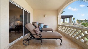 A balcony with a cushioned chair, a small table, and decorative vases.