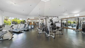 Un gimnasio con cintas de correr, máquinas de pesas y un espejo grande.