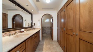 Un baño con tocador, espejo y armarios de madera.