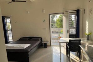 Une chambre à coucher avec un lit, un bureau et une chaise. Il y a une fenêtre avec des rideaux et une vue sur l’extérieur.