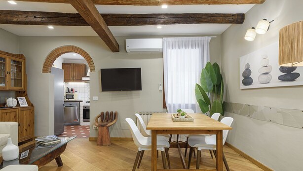 A modern kitchen with an archway, a dining area with a wooden table and white chairs, and a large green plant. - Santo Spirito: Florence's Residential Soul apartment (Firenze)