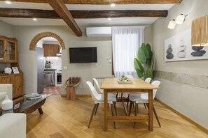 A modern kitchen with an archway, a dining area with a wooden table and white chairs, and a large green plant.
