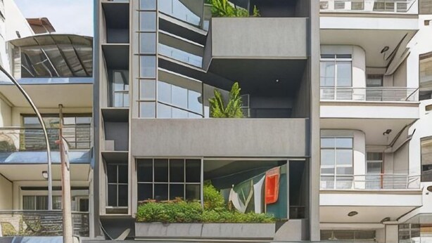 Un edificio de varios pisos con balcones, ventanas amplias y algo de vegetación.