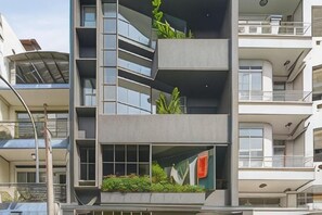 A multi-story building with balconies, large windows, and some greenery. - Express by M Village Dinh Cong Trang, a brand of Modern Village Lifestyle (Ho Chi Minh City)