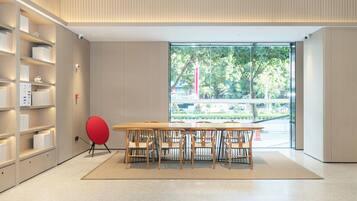A modern interior with a wooden table and chairs, a red chair, and a bookshelf.