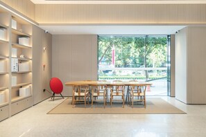 A modern interior with a wooden table and chairs, a red chair, and a bookshelf. - Ji Hotel Guangzhou Fangcun Huadiwan (Guangzhou)