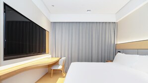 Une chambre d’hôtel moderne, dotée d’un grand lit, d’un bureau et d’une chaise.