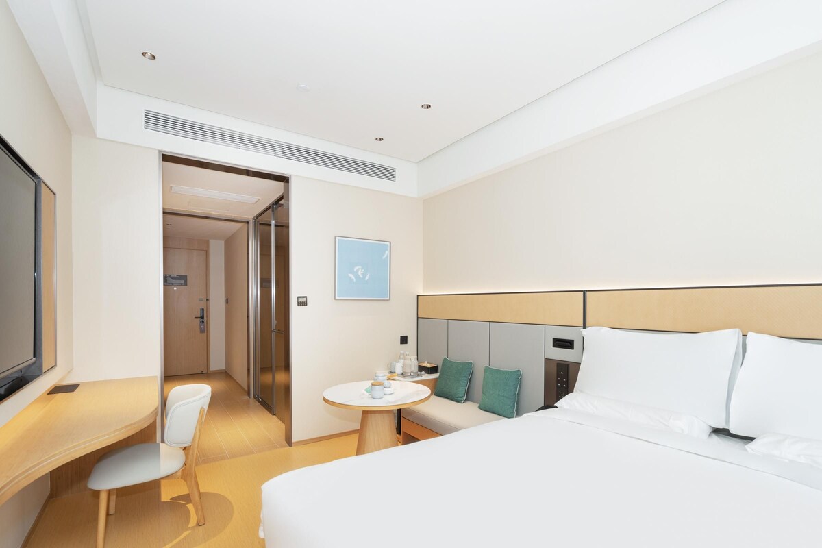 Una habitación de hotel moderna con una cama, un escritorio, una silla y una mesita.