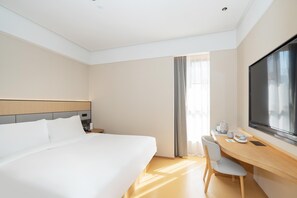 A hotel room with a large bed, a desk with a chair, a flat-screen TV, and a window with curtains. - Ji Hotel Guangzhou Fangcun Huadiwan (Guangzhou)