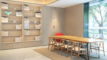 Una biblioteca moderna con una larga mesa de madera y sillas, rodeada de estanterías.