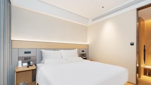 Une chambre d’hôtel dotée d’un grand lit, de tables de chevet, d’une commode et présentant un design moderne.