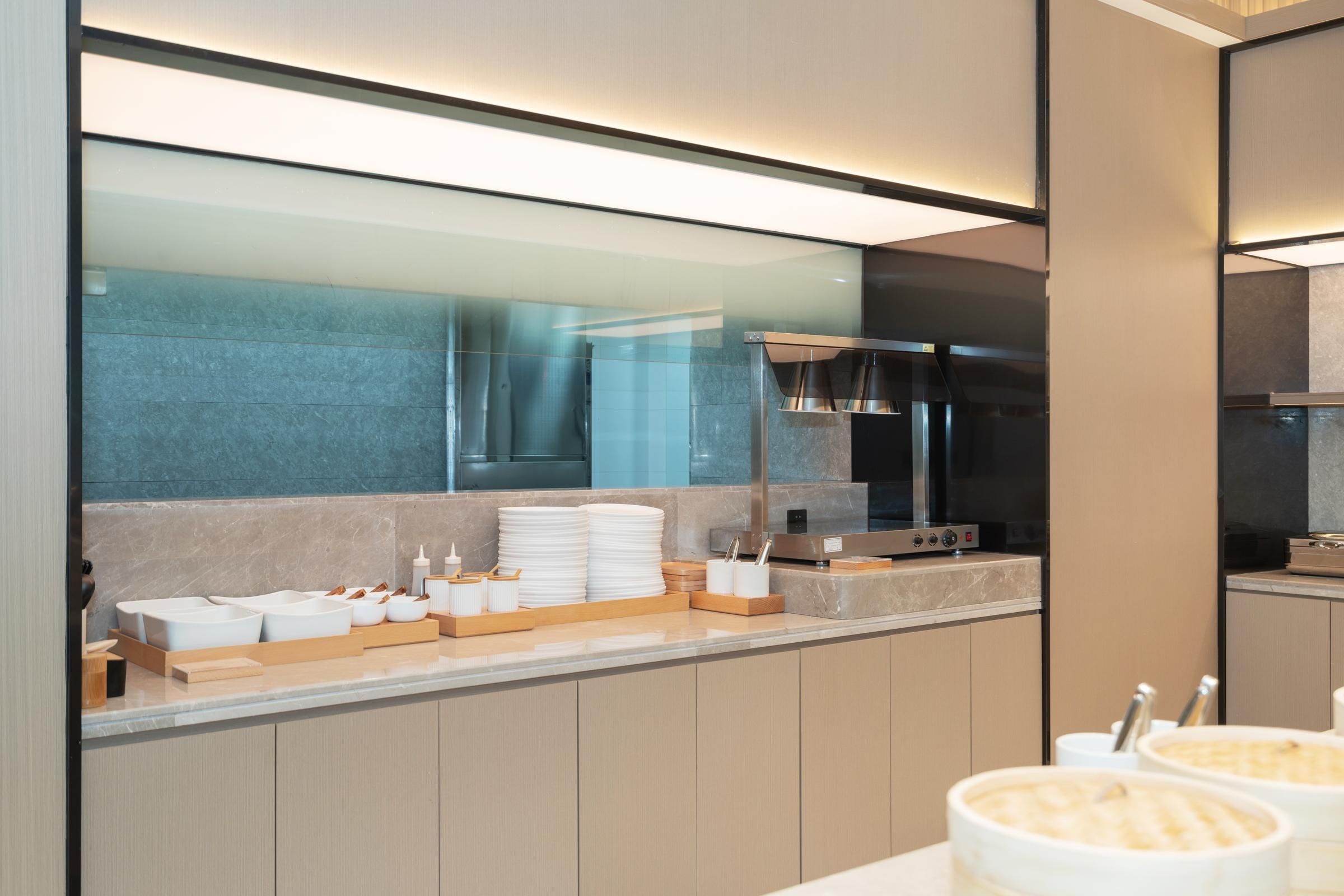 A modern kitchen with a marble countertop, stainless steel appliances, and a glass partition.