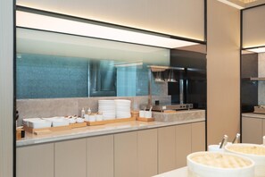 A modern kitchen with a marble countertop, stainless steel appliances, and a glass partition. - Ji Hotel Guangzhou Fangcun Huadiwan (Guangzhou)