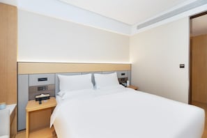 A modern hotel room with a large bed, a bedside table with a phone and a lamp, and a wooden headboard. - Ji Hotel Guangzhou Fangcun Huadiwan (Guangzhou)