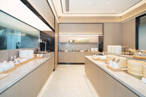 A modern kitchen with a long countertop, stainless steel appliances, and neatly arranged food items. - Ji Hotel Guangzhou Fangcun Huadiwan (Guangzhou)