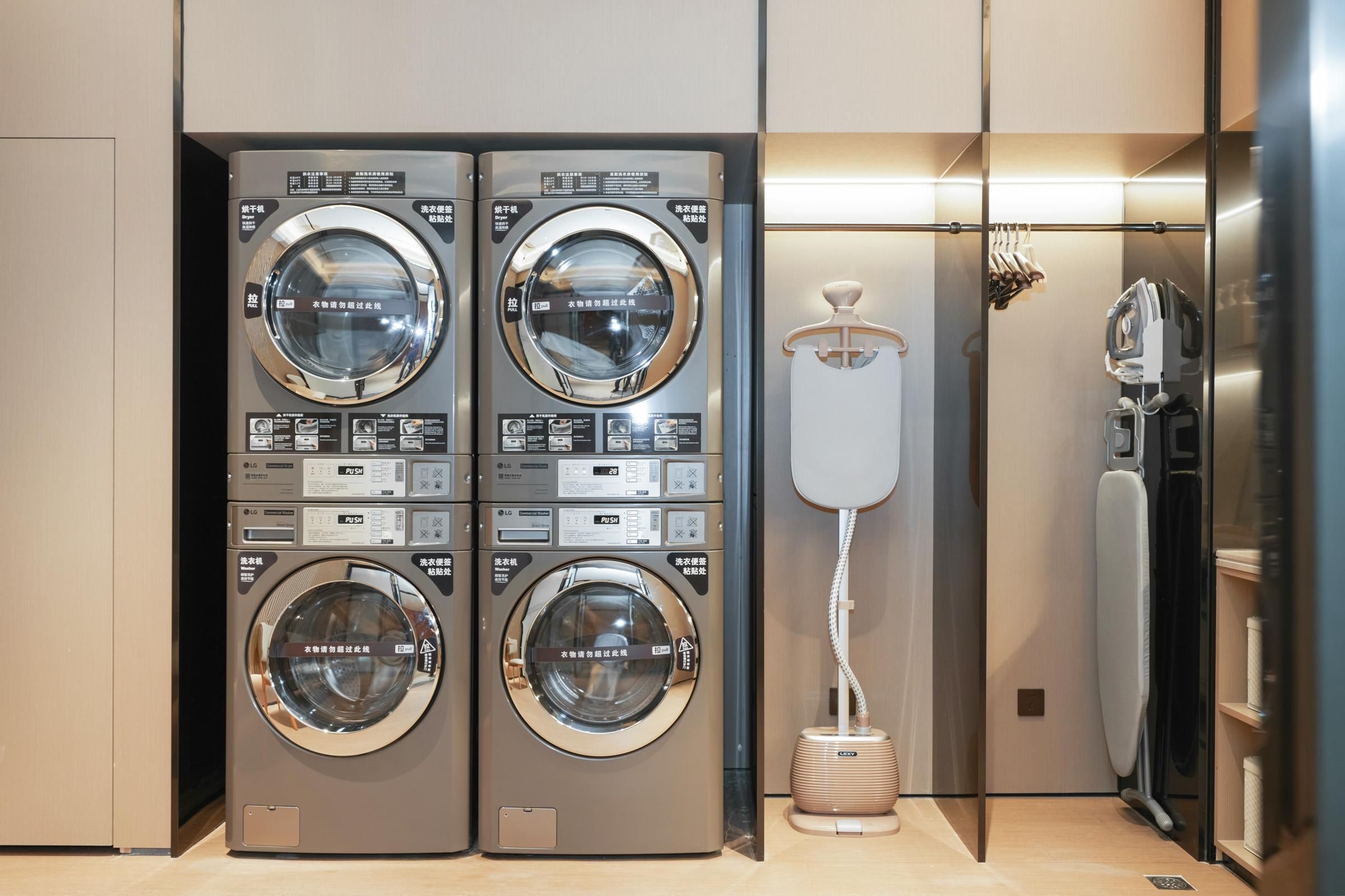 A modern laundry facility with two stacked washing machines and a drying machine.